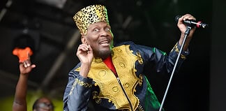 Jimmy Cliff, Reggae Iconoclast and Legend, dies at 81 Energetic performer wearing traditional African attire singing on stage.